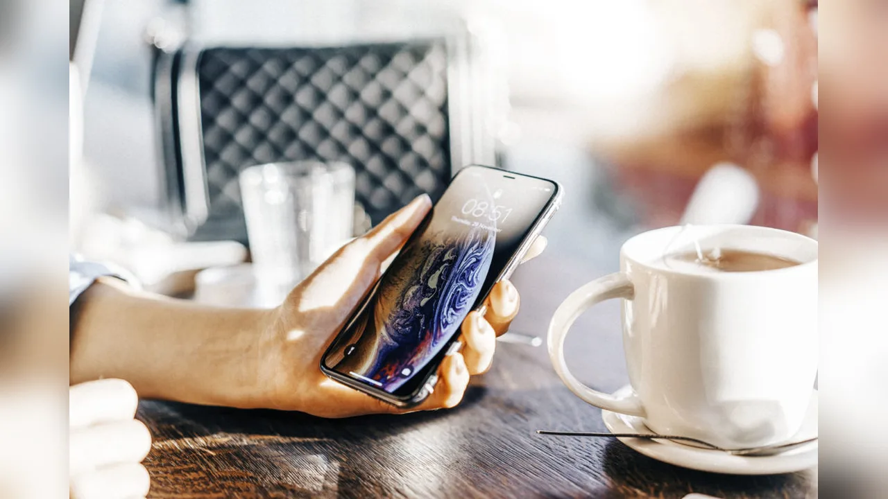 A cup of coffee and a phone on a table in the morning light